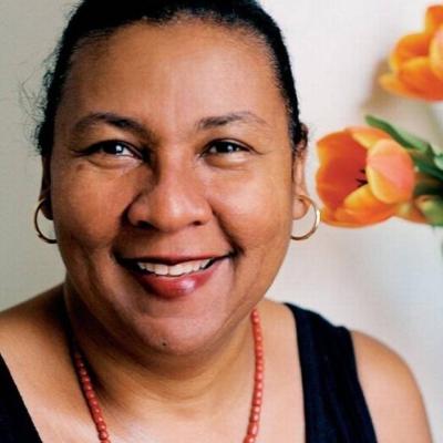 Headshot of writer and feminist critic bell hooks with hair pulled back, wearing a black tank top, red beaded necklace, and gold hoop earrings