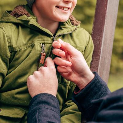 Man helps boy zip jacket.